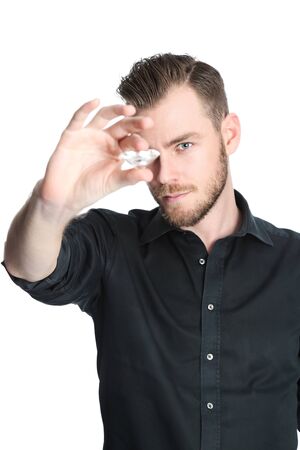 A man in his 20s, wearing a black shirt, standing with a large diamond in his hand, inspecting. White background.の写真素材