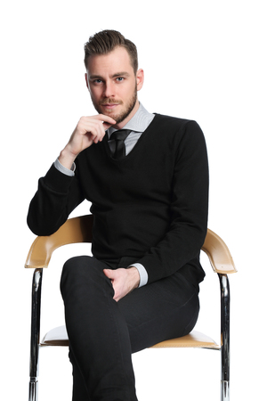 Handsome and laid back businessman sitting down in an arm chair, feeling satisfied. White background.の写真素材