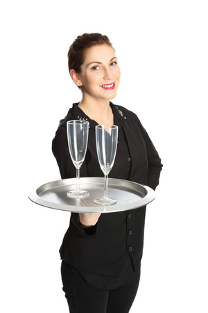 A cute brunette waiter serving two glasses of champagne on a serving tray, wearing a black shirt with a black vest. White background.の写真素材