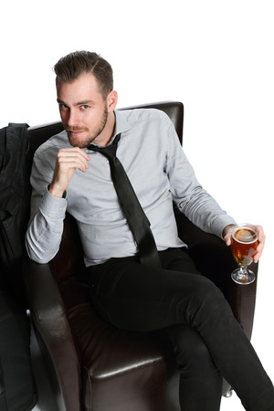 A businessman sitting down relaxing in a lounge chair with a beer. Looking at camera with white background.の写真素材