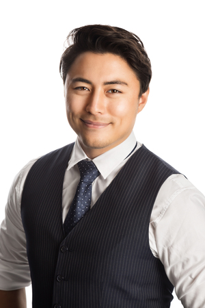 Mature smiling businessman standing against a white background wearing a blue suit, shirt, vest and tie, looking at camera.の写真素材