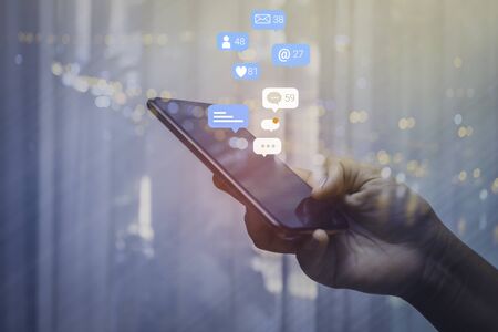 Person using a social media marketing concept on mobile phone with notification icons of like, message, comment and star above smartphone screen.の写真素材