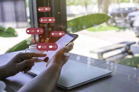 Person using a social media marketing concept on mobile phone with notification icons of like, message, comment and star above smartphone screen.の写真素材