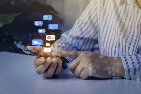 Person using a social media marketing concept on mobile phone with notification icons of like, message, comment and star above smartphone screen.の写真素材