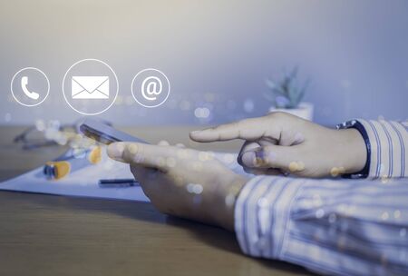 Contact us or Customer support hotline people connect. Businessman using a mobile phone with the (email, call phone, mail) icons.の写真素材