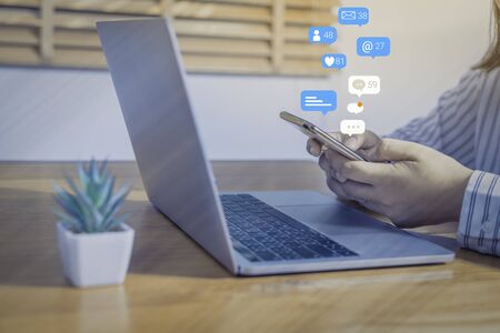 Person using a social media marketing concept on mobile phone with notification icons of like, message, comment and star above smartphone screen.の写真素材