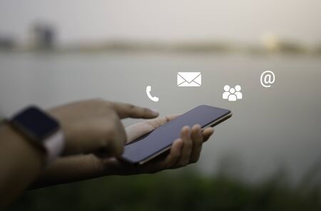 Contact us or Customer support hotline people connect. Businessman using a mobile phone with the (email, call phone, mail) icons.の写真素材