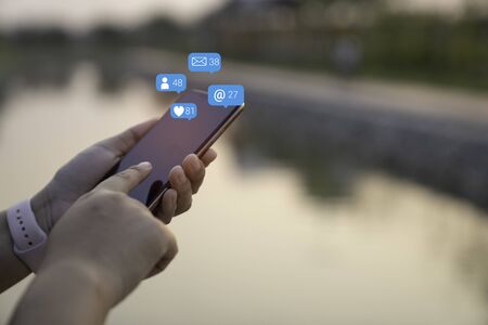 Person using a social media marketing concept on mobile phone with notification icons of like,...