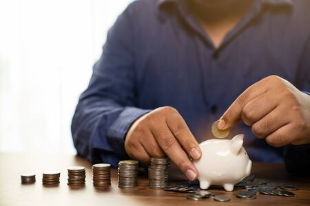 Businessman holding coins putting in piggy bank, concept saving money for finance accountingの写真素材