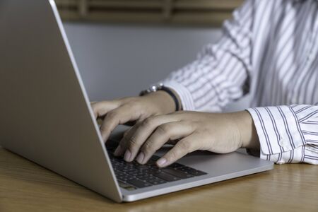 Manager working on a project in open space office. Laptop on wooden table.