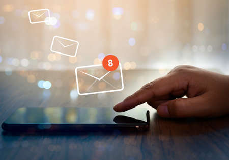 Businesswoman hand using smartphone on table in office with 8 new email alert sign icon pop-up. Mail...