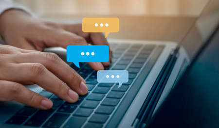 Person hand using laptop typing, chatting conversation in chat bubble pop-up. Social media maketing...