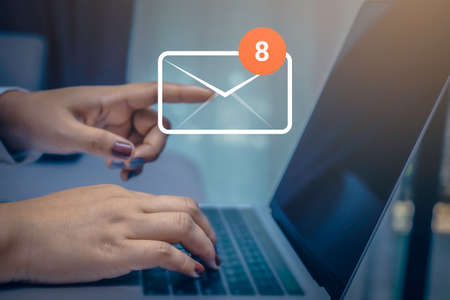 Businesswoman hand using laptop on table in office with 8 new email alert sign icon pop-up. Mail communication connection message technology.の写真素材