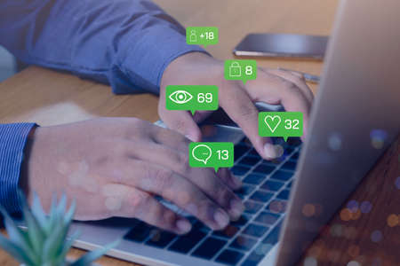 Person using a social media marketing concept on laptop with notification icons of like, chat,...