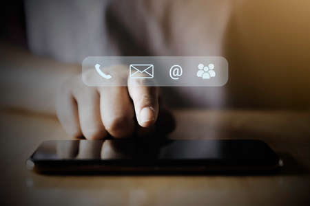 Contact us or Customer support hotline people connect. Businessman using a mobile phone with the (email, call phone, mail) icons.の写真素材