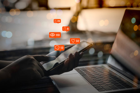Person hand using a mobile phone and laptop with social media marketing concept.の写真素材