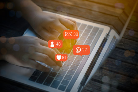 Person hand using a mobile phone and laptop with social media marketing concept.