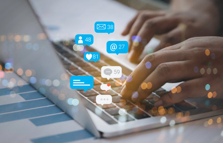 Person using a social media marketing concept on computer laptop with notification icons of like, chat, message and comment above laptop screen.の写真素材