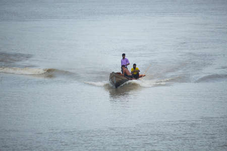 A wooden boat is running in the riverのeditorial素材