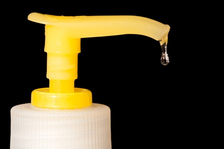 Soap dripping from a soap dispenser over black backgroundの写真素材