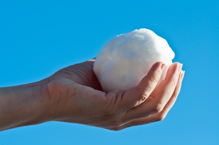 Female holding a snow ball in sunlight with blue sky as backgroundの写真素材