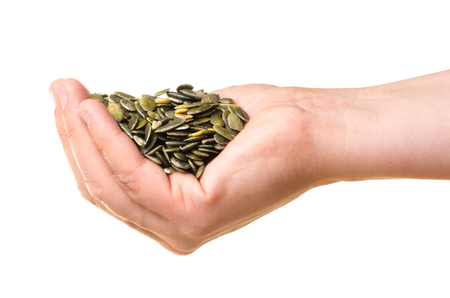 Pumpkin seeds in a hand isolated on white backgroundの写真素材