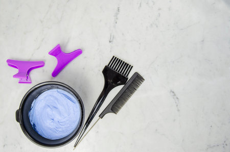 dye tools for bleaching hair, mixing bowl, brush, comb, hair clips, and disposable gloves on marbled backgroundの写真素材