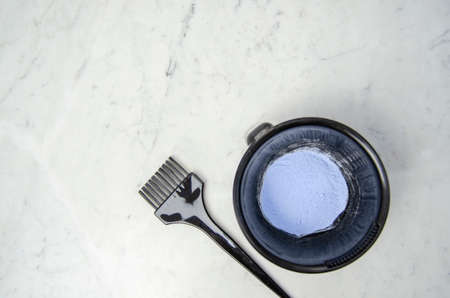 dye tools for bleaching hair, mixing bowl, brush, comb, hair clips, and disposable gloves on marbled backgroundの写真素材