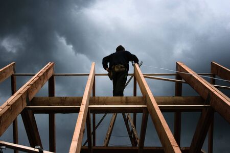 roofer on a roof framework in front of a cloudy skyの写真素材