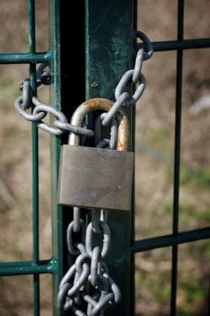 a padlock with an iron chain at a fenceの写真素材