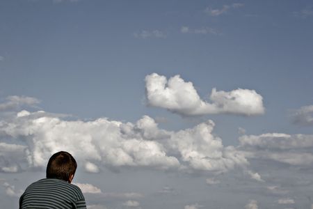 boy is looking into a dramatically cloudy sky