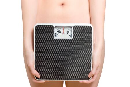 Woman holds a scale in front of her hip, showing only the belly buttonの写真素材
