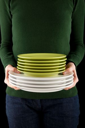 female hands holding a pile of green and white dishes