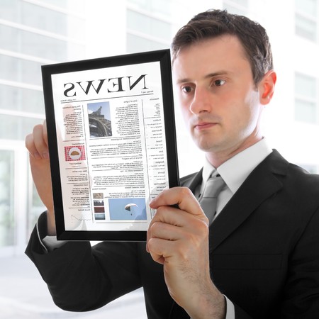 Businessman holding a touchpad pc and reading a newspaperの写真素材