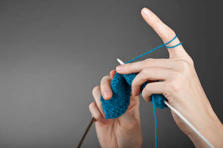 Hands of a young woman knitting with blue woolの写真素材