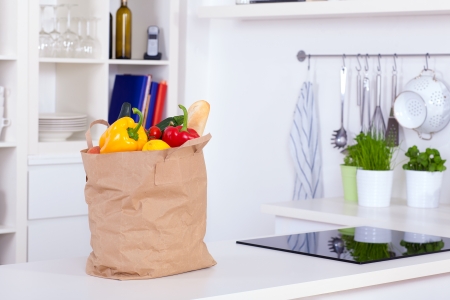 Paper shopping bag full of food on a kitchen counterの写真素材