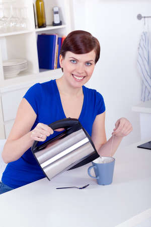 beautiful young happy young woman preparing tea at home in the morningの写真素材