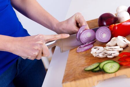 female hands chopping vegetables on a wooden board in the kitchenの写真素材