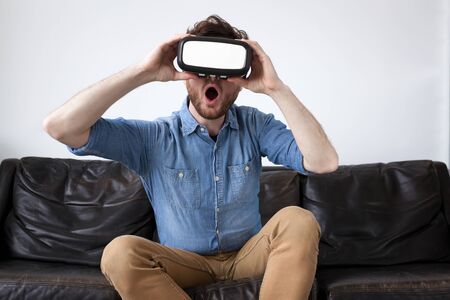 Man on a couch wearing virtual reality gogglesの写真素材