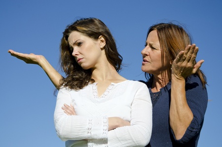 Mother discussing with her ignoring and stubborn looking daughter who turned her back on herの写真素材