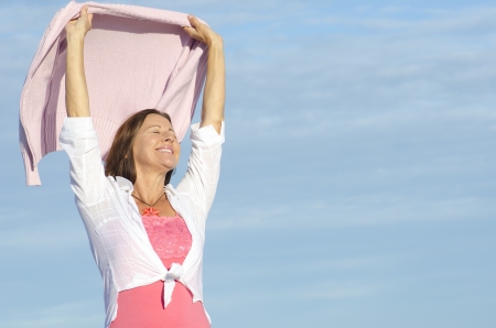 Cheerful, happy smiling attractive senior woman enjoying retirement, isolated, with blue sky as background and copy space.の写真素材