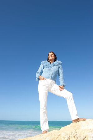 Happy, confident and sexy looking senior woman enjoying relaxed sun at beach, isolated with ocean and blue sky as background and copy space の写真素材