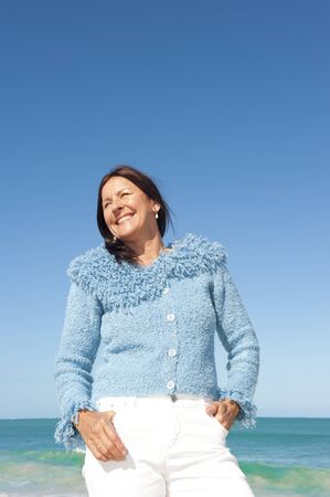 Happy, confident and sexy looking senior woman enjoying relaxed sun at beach, isolated with ocean and blue sky as background and copy space の写真素材