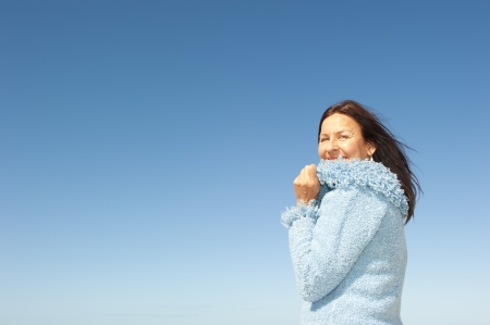 Portrait of confident and happy relaxed looking attractive senior woman enjoying active retirement in winter sun, isolated with blue sky as background and copy space の写真素材