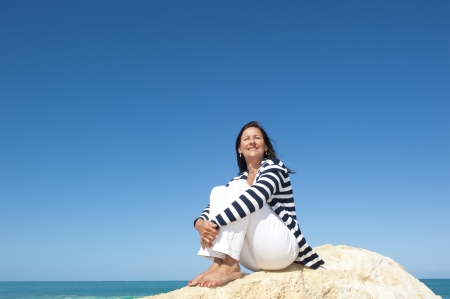 Happy confident and attractive senior woman  relaxed active retirement holiday at sea, isolated with ocean and blue sky as background and copy space.の写真素材