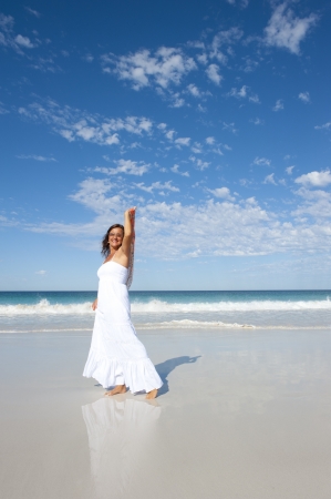 Sexy pretty middle aged woman cheerful, joyful in white summer dress at beach, isolated with ocean and blue sky as background and copy space.の写真素材