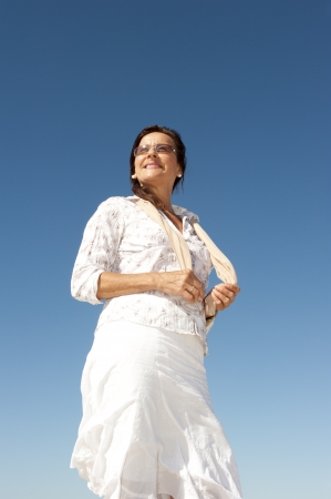 Attractive and happy middle aged woman relaxed and casual enjoying active retirement, isolated with blue sky as background and copy space の写真素材