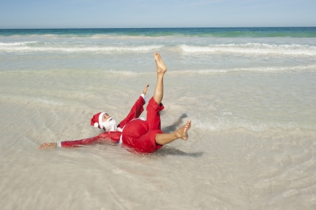 Santa Claus happy lying in shallow water at beachの写真素材