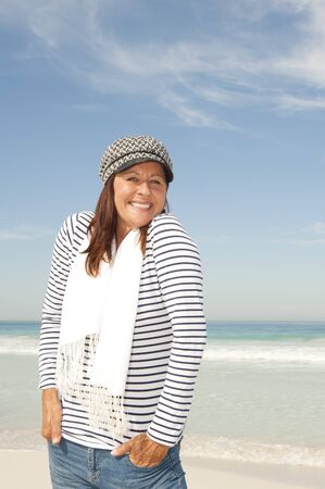 Portrait beautiful looking mature woman with happy smile, wearing sporty shirt and capの写真素材
