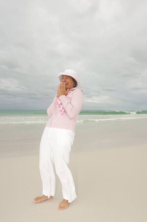 Attractive, cheerful and confident looking middle aged woman at beach enjoying active retirement holiday, isolated with storm clouds in the sky and ocean as background and copy space.の写真素材